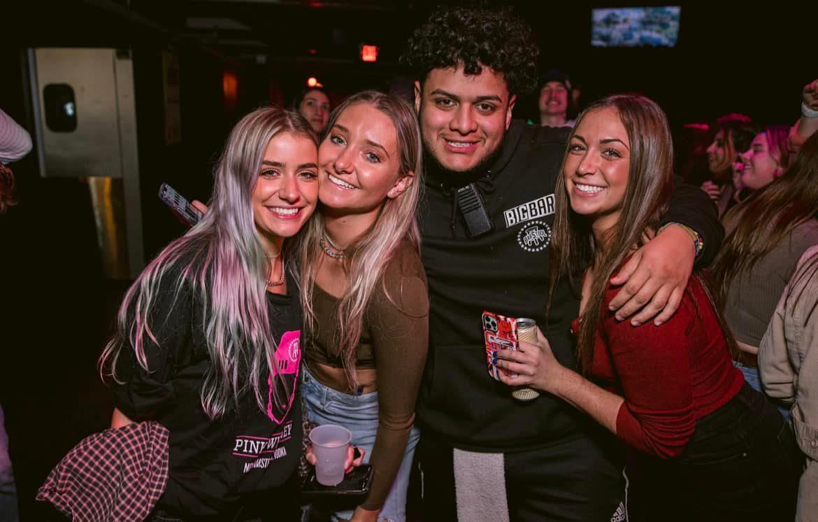 four people smiling at Big Bar Columbus near OSU