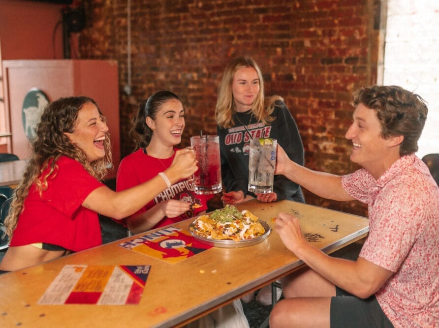 four people at Ethyl and Tank eating nachos and drinking near osu in columbus