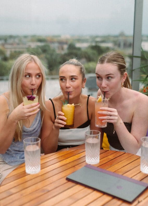 3 girls sipping on colorful cocktails in the Short North near OSU