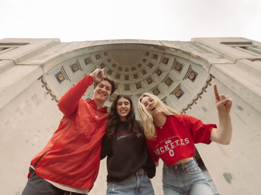 3 students cheering outside the shoe at Ohio State