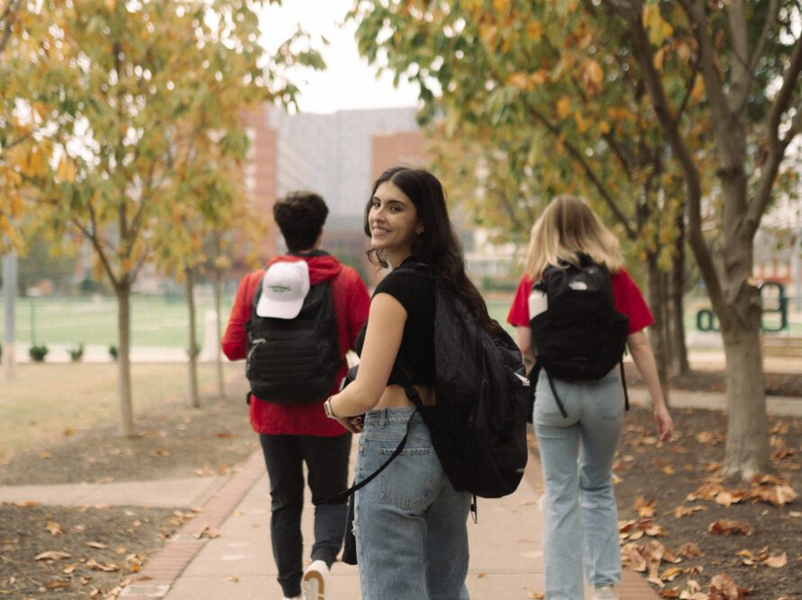 Girl looking back and smiling as she is walking on the ohio state campus