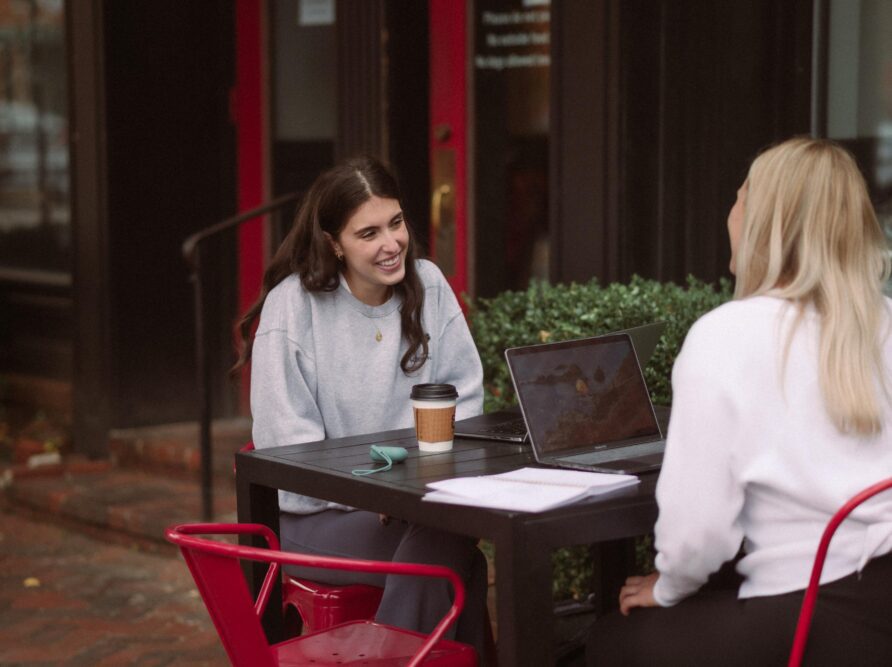 two girls at coffee while working on a computer