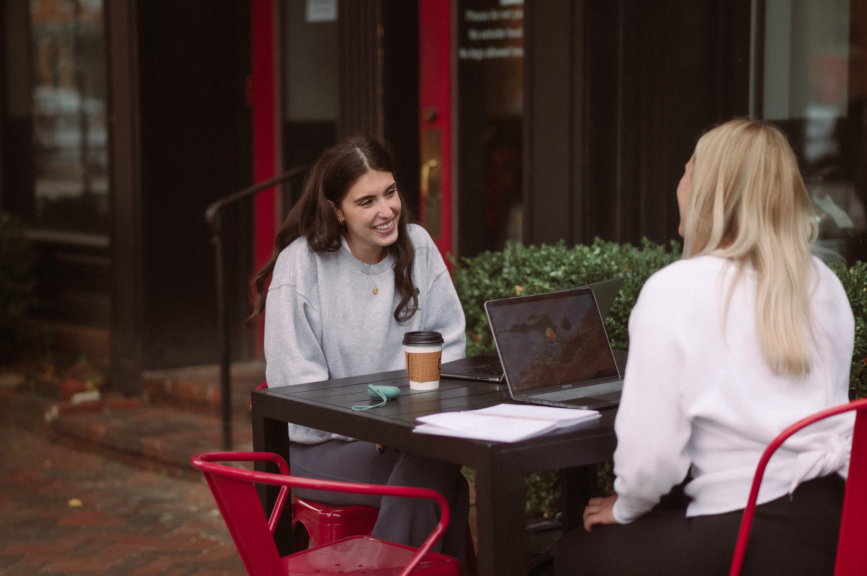 two girls at coffee while working on a computer